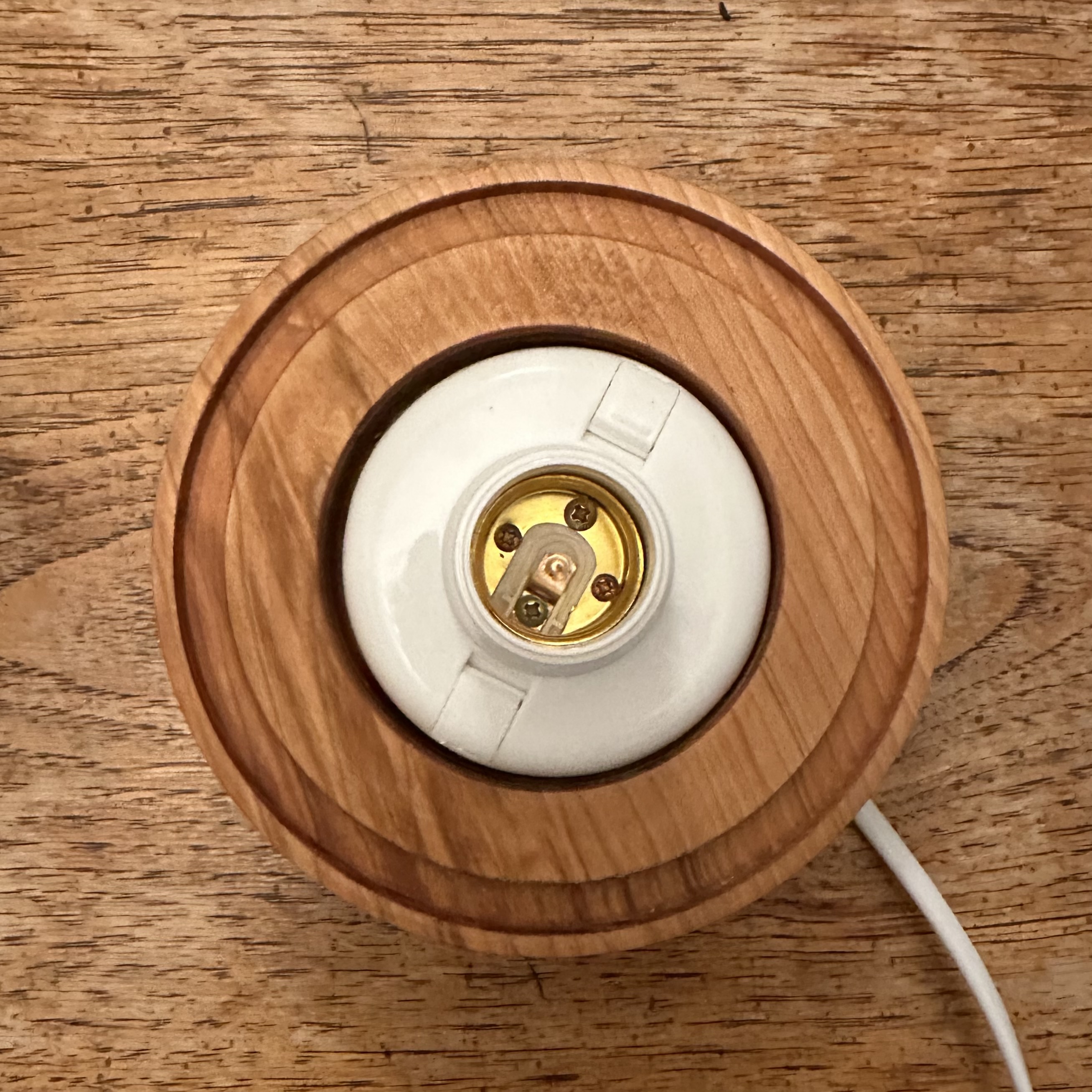 Wooden base carved out to fit the ceramic lampshade, with lighting fixture attached inside